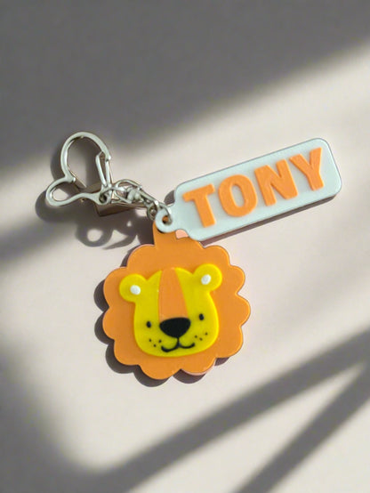 Keychain with lion design and 'TONY' tag on a wooden surface