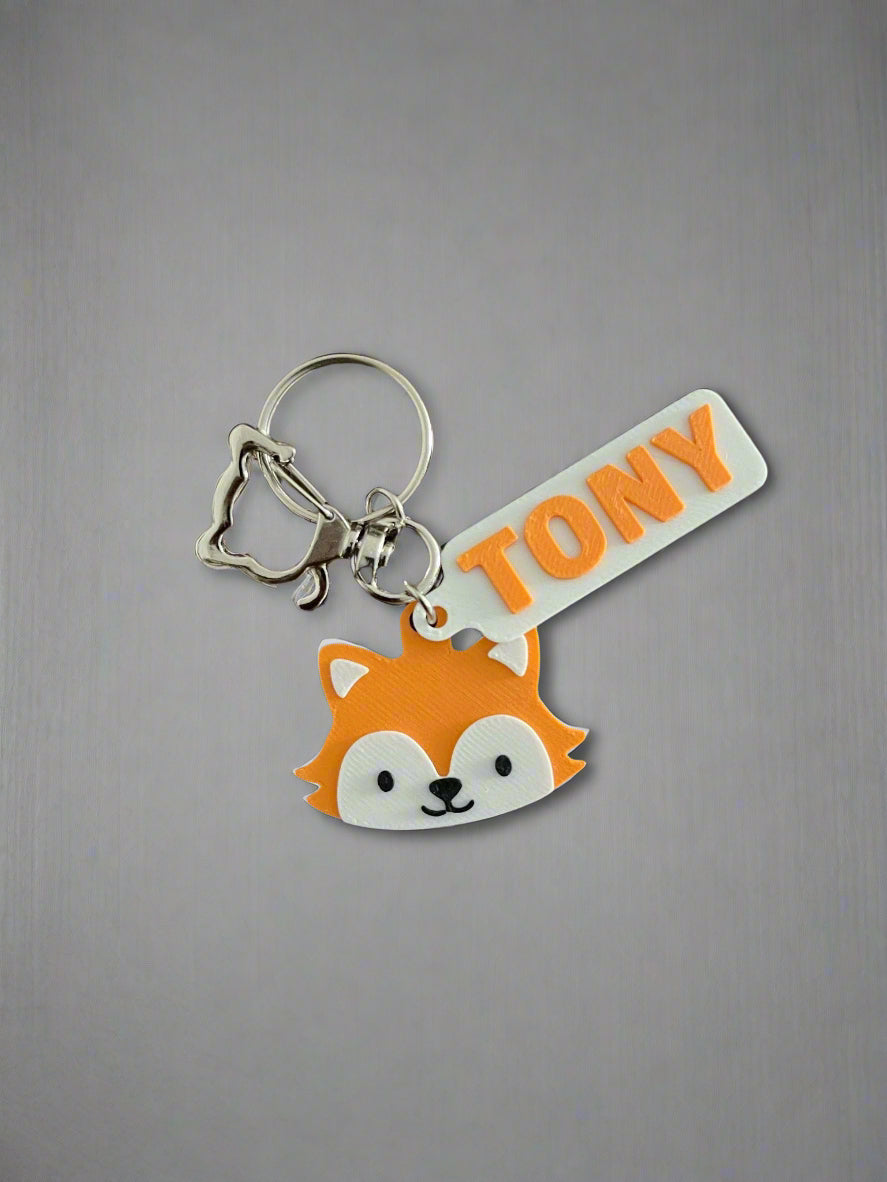 Keychain with fox design and 'TONY' tag on a wooden surface